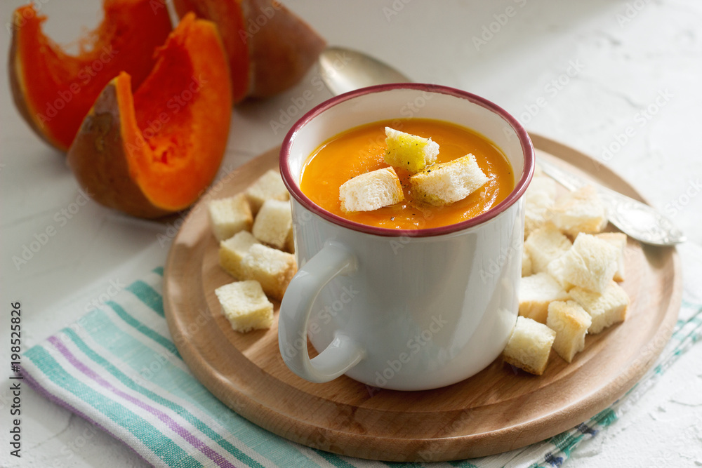 Delicate vegetable cream soup with pumpkin and croutons and slices of pumpkin on a light background. Delicate vegetable cream soup with pumpkin and croutons and slices of pumpkin on a light background.