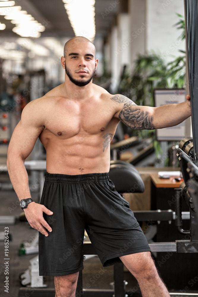 Naklejka premium Young handsome sporty muscular man posing in gym