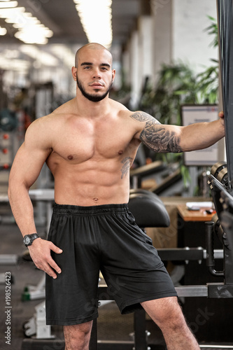 Young handsome sporty muscular man posing in gym