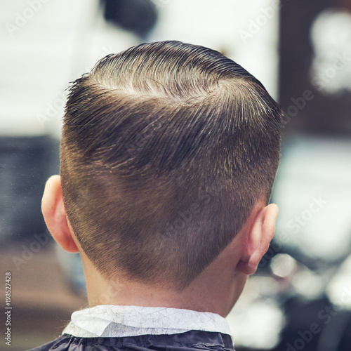 Boy getting hairstyle in barbershop in London.