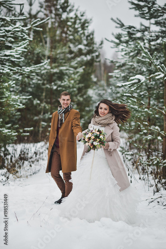 Newlyweds walk among snow-covered trees and pines 841. © alenazamotaeva
