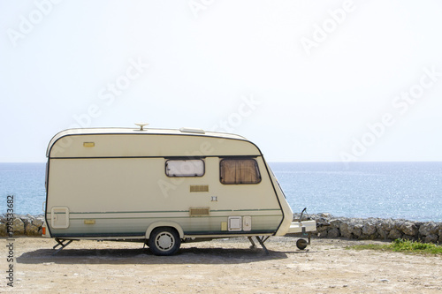 Caravan on the sand beach with the blue sea on background