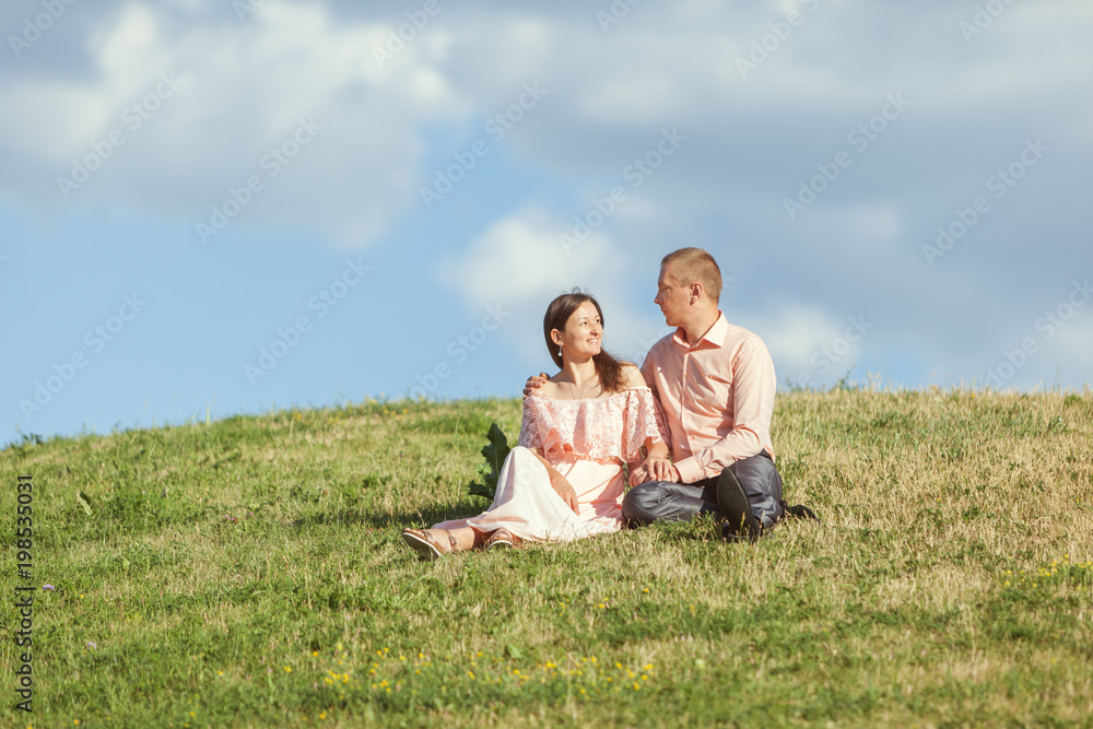 Young loving couple sitting on a hill. Young loving couple sitting on a hill.
