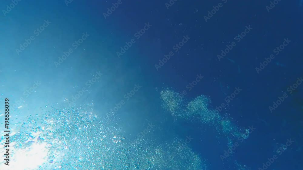Swimming pool bubbles, sea or ocean wave underwater over blue sunny sky background. Sun and sunlight rays with copy space. Shot with GOPRO HERO4 4K UHD video. Swimming pool bubbles, sea or ocean wave underwater over blue sunny sky background. Sun and sunlight rays with copy space. Shot with GOPRO HERO4 4K UHD video.