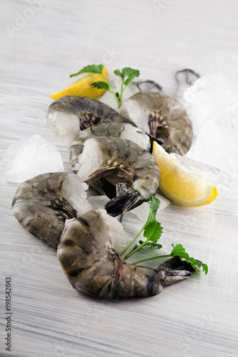 Fotografia fresh king prawns with lemon and lemon balm on white wooden kitchen plate can be