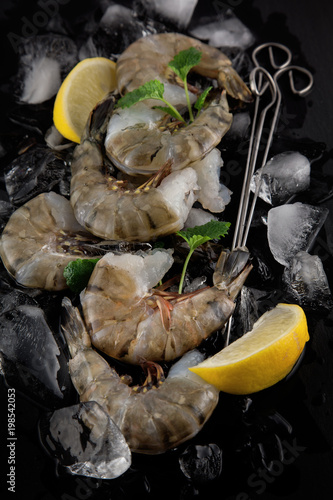 fresh raw king prawns with lemon and lemon balm on dark slate kitchen plate with napkin can be used as background