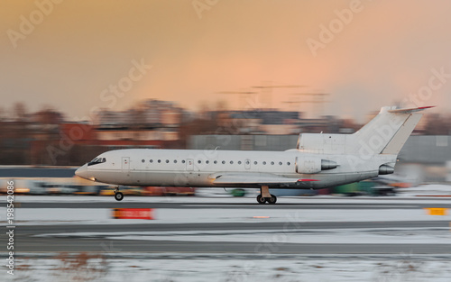 Narrow-body regional passenger airplane taking off at sunset, side view in motion, dramatic sky on background.Aviation concept