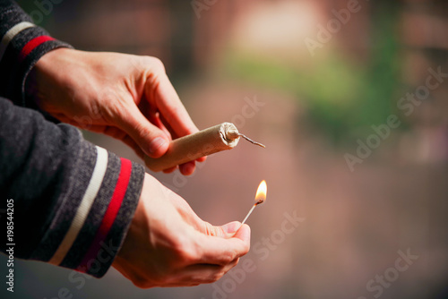 Close up of man hand lighting up a firecrackers in a burred background photo