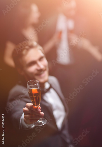 stylish young man standing with a glass of champagne.