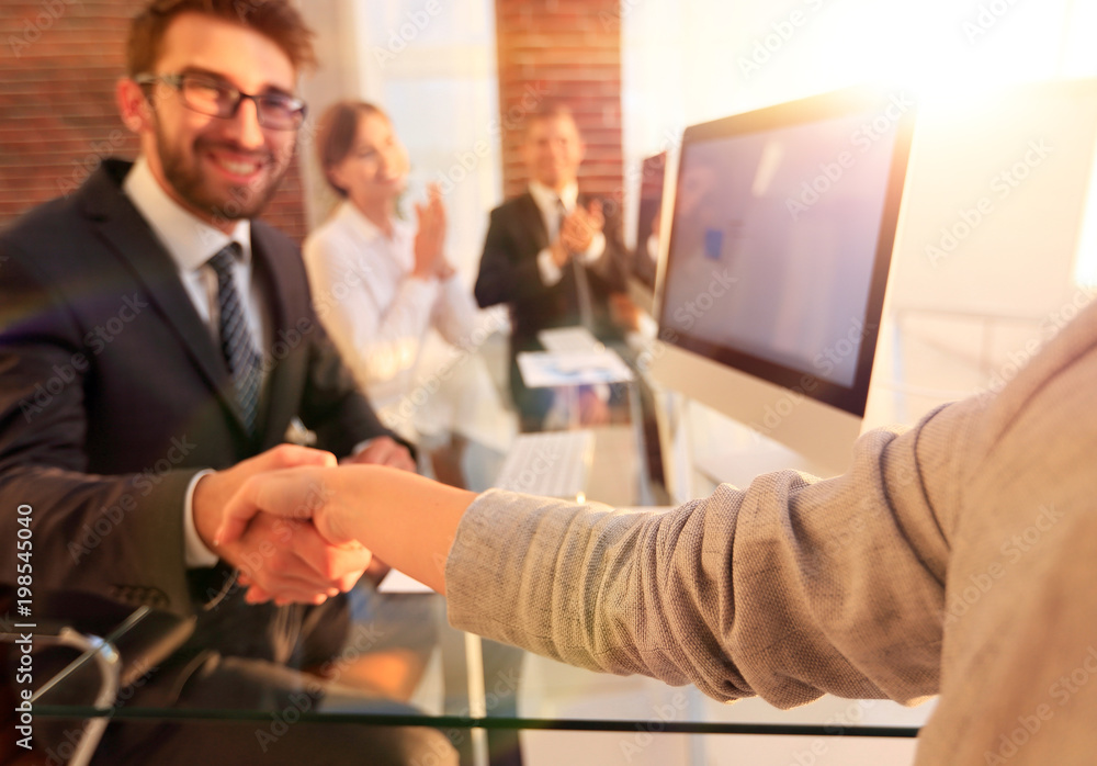 Fototapeta premium businessman shaking hands with a business partner sitting near your desktop