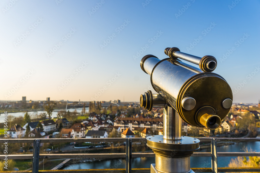 Overlooking view on the city with a binocular in the foreground, with a graduated blue sky and copy space, Kehl, Germany.