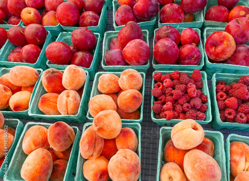 Green cardboard baskets with peaches, plums and raspberries