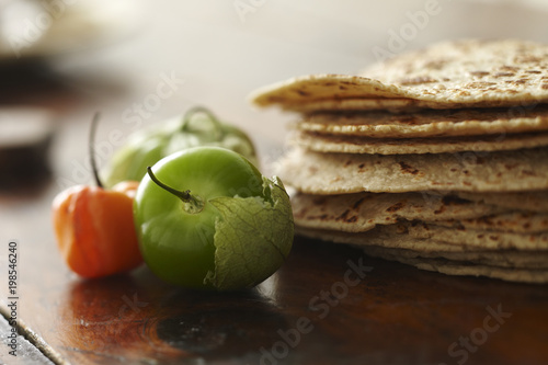 Close-up of tomato, chili pepper, and tortillas on the table