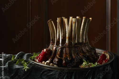 Rack of lamb with pomegranate on a plate with herbs and pistachios