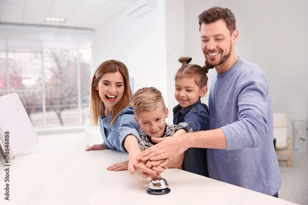 Family ringing service bell on reception desk in hotel Family ringing service bell on reception desk in hotel