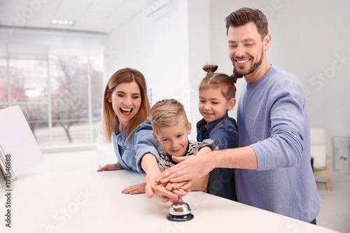 Family ringing service bell on reception desk in hotel