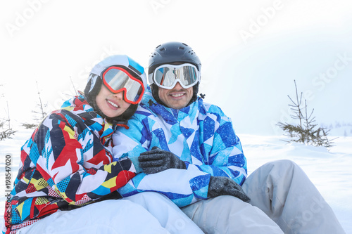 Happy couple sitting on snow at ski resort. Winter vacation © Africa Studio