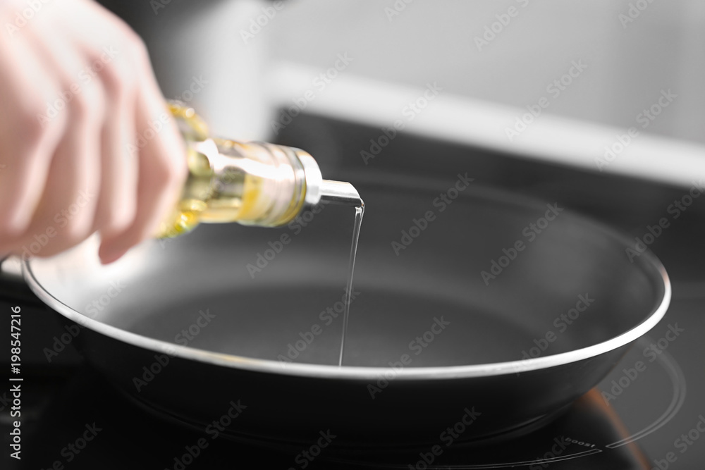 Woman pouring cooking oil into frying pan, closeup Woman pouring cooking oil into frying pan, closeup