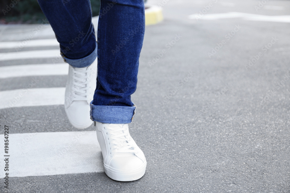 Stylish man in white shoes walking across the city street Stylish man in white shoes walking across the city street
