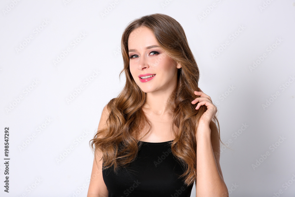 Portrait of young woman with long beautiful hair on light background Portrait of young woman with long beautiful hair on light background