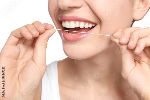 Young woman flossing her teeth on white background  closeup