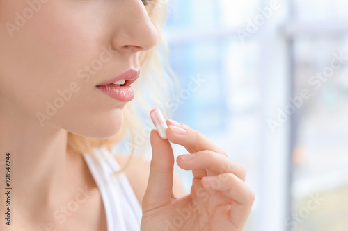 Young woman taking pill indoors