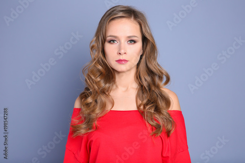 Portrait of young woman with long beautiful hair on grey background