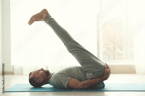 Sporty man practicing yoga indoors