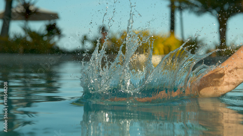 CLOSE UP  Unrecognizable woman slaps the smooth surface of still pool water.