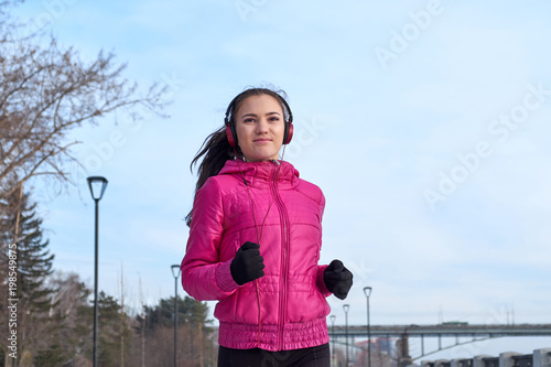 Running athlete woman sprinting during winter training outside in cold snow weather. Close up showing speed and movement. photo