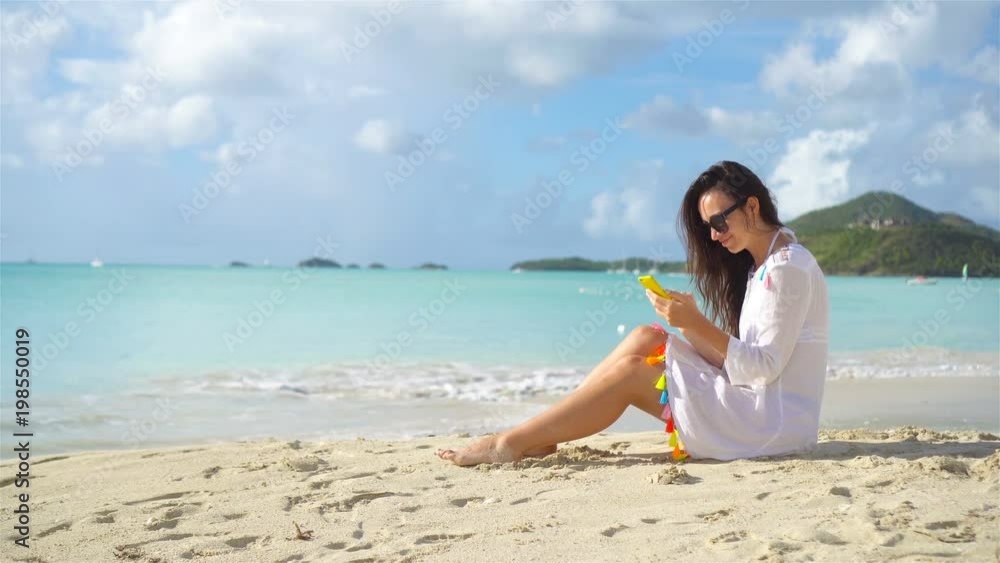 Young woman with smartphone during tropical beach vacation. Beautiful girl on the beach with cellphone on caribbean island. Young woman with smartphone during tropical beach vacation. Beautiful girl on the beach with cellphone on caribbean island.