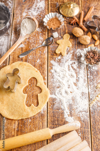 The process of making classic ginger biscuits in the form of little men. Still life on a wooden background with ingredients and figurines. photo