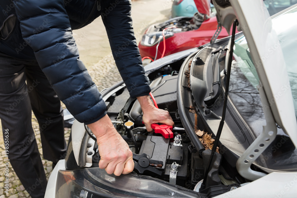 Person Using Jumper Cables To Charge Car's Dead Battery Person Using Jumper Cables To Charge Car's Dead Battery
