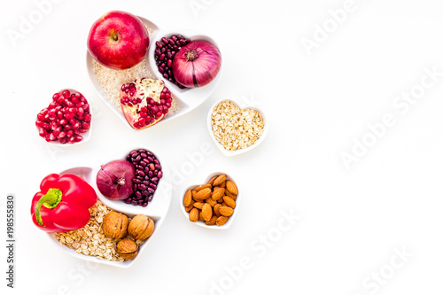 Diet for healthy heart. Food with antioxidants. Vegetables, fruits, nuts in heart shaped bowl on white background top view copy space