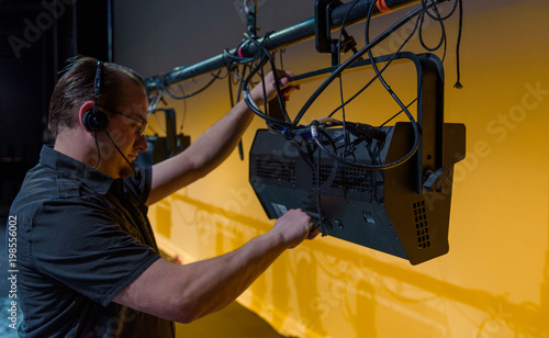 Male theater technician adjusting theatrical lighting units
