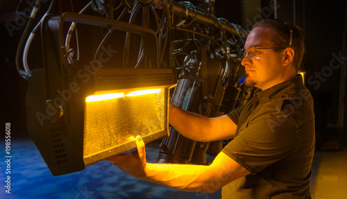 Male theater technician adjusting theatrical lighting units