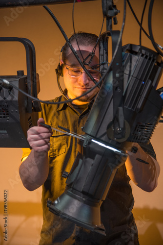 Male theater technician adjusting theatrical lighting units