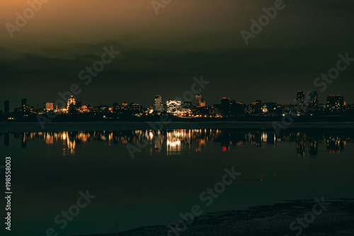 Night city view with lots of lights and its reflection in a river water © kapichka