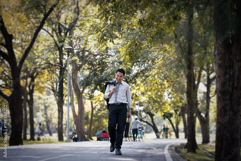 Young Asia businessman happy face. He was walking in the Park. Young Asia businessman happy face. He was walking in the Park.