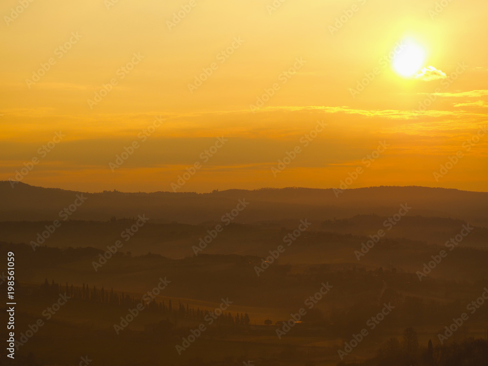 Sunrise in the lands of Tuscany. Warm colors on the hills and haze