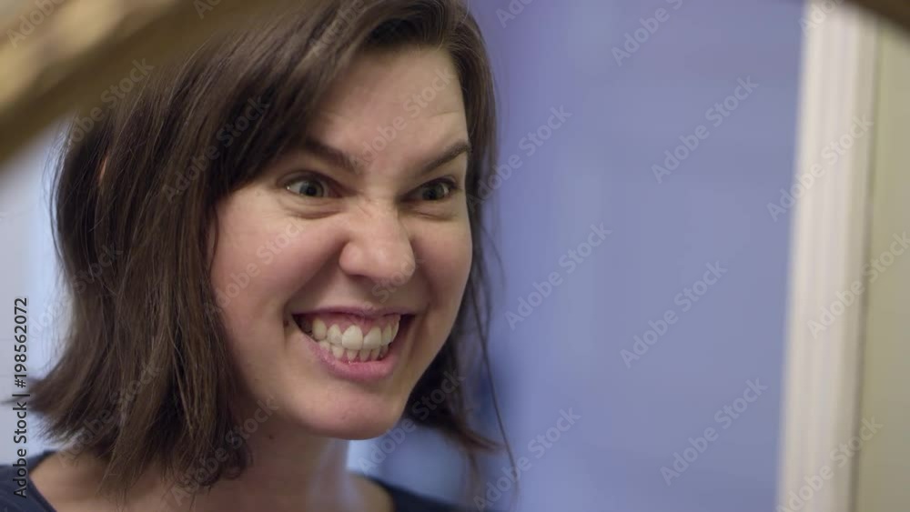 Woman looking in the mirror and making funny faces ash she talks to herself. Woman looking in the mirror and making funny faces ash she talks to herself.