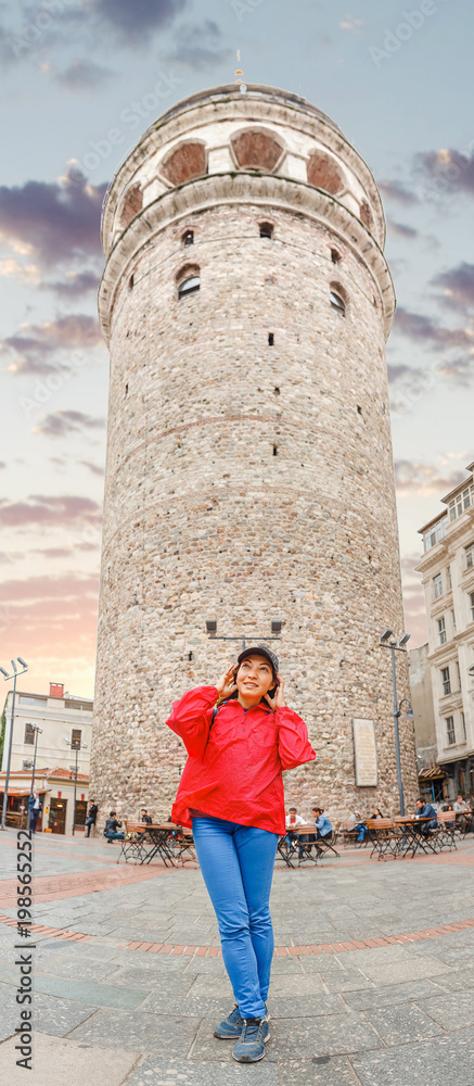 Young happy tourist woman walking near Galata Tower and the street in the Old Town of Istanbul, Turkey