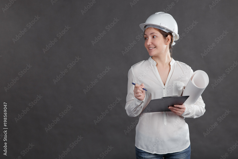 Young female architect in a protective helmet making notes on the project