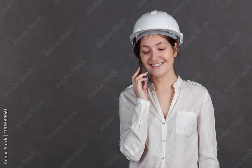 Young woman in a protective helmet talking on the phone Young woman in a protective helmet talking on the phone