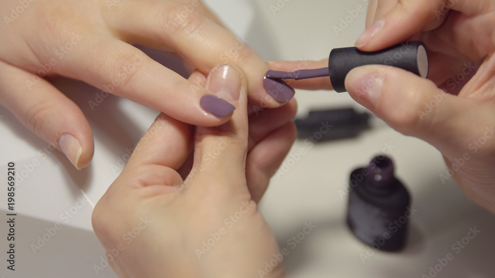 Nail care in the salon. Master applies gel-lacquer on the nails of a young woman