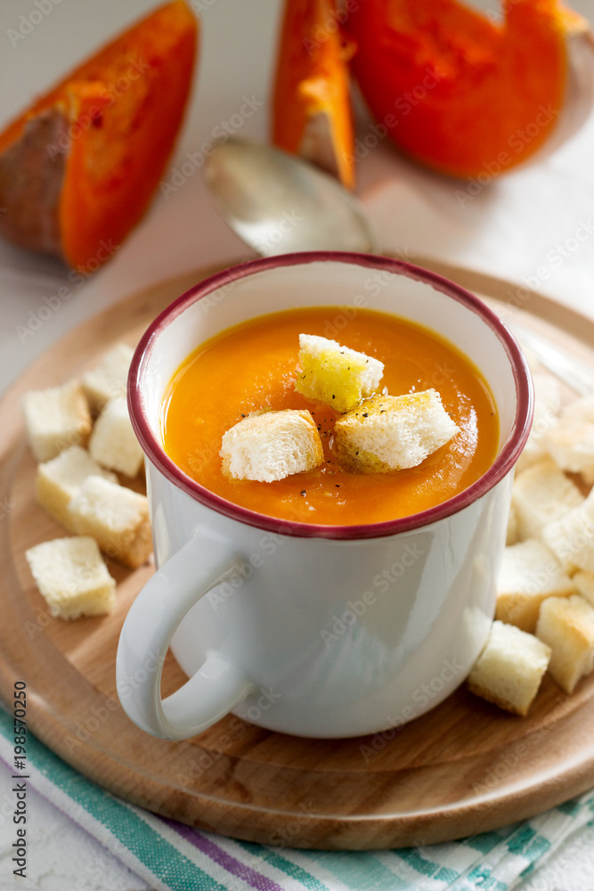 Delicate vegetable cream soup with pumpkin and croutons and slices of pumpkin on a light background. Delicate vegetable cream soup with pumpkin and croutons and slices of pumpkin on a light background.
