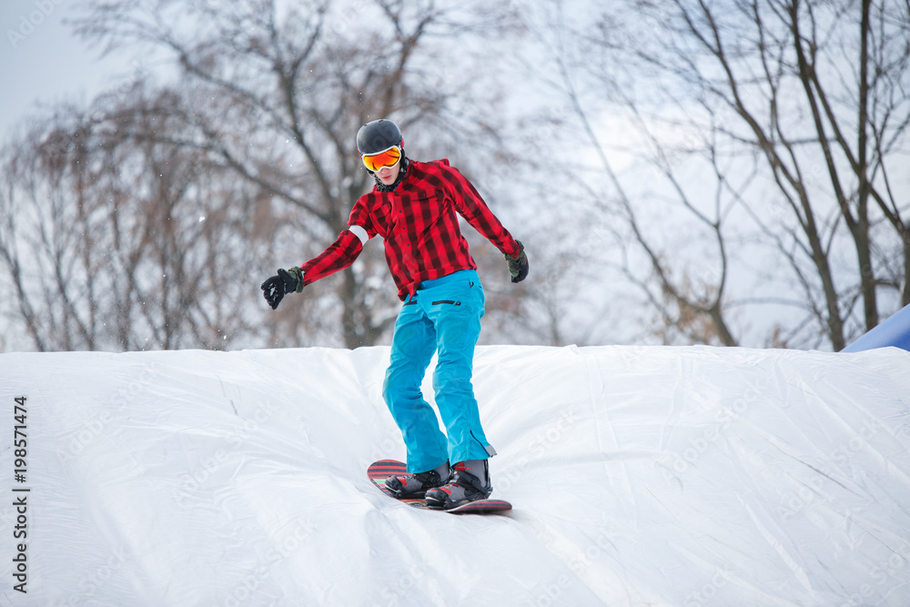 Picture of man wearing helmet riding snowboard from snow slope