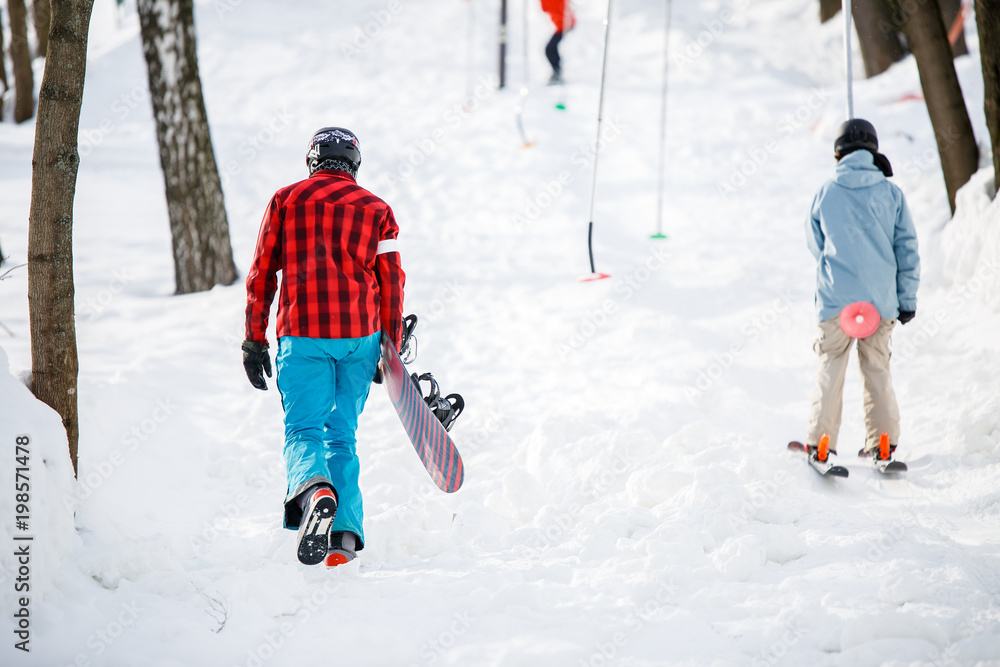 Photo of walking snowboarders from back in winter park Photo of walking snowboarders from back in winter park
