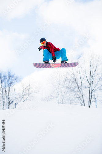 Picture of athlete with snowboard jumping in snowy resort