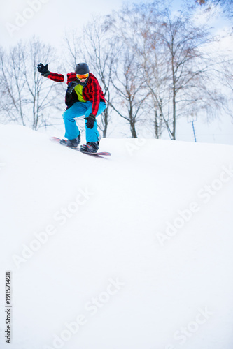 Image of sportsman in helmet with snowboard riding in snowy resort